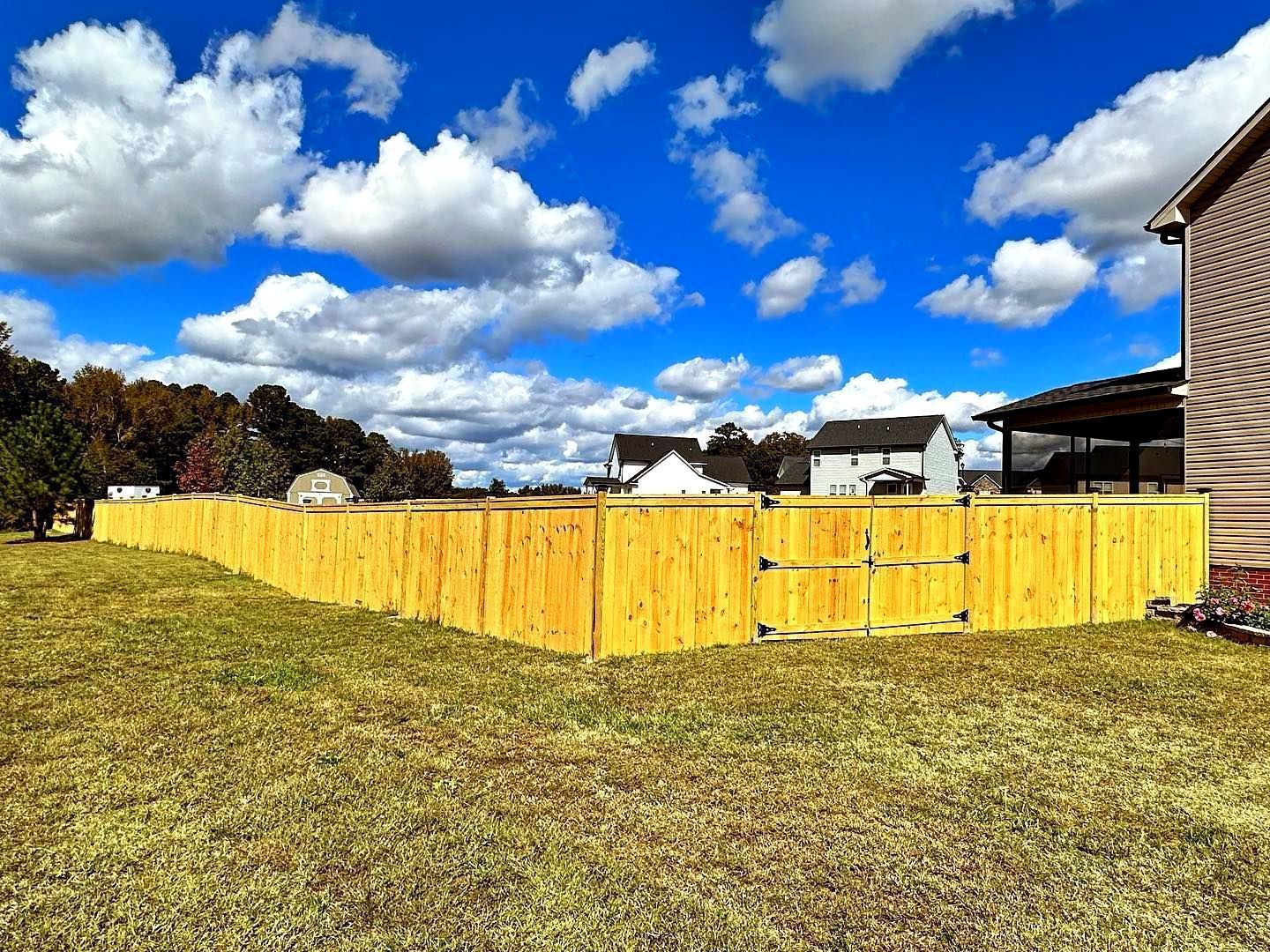 A wooden fence is in the middle of a grassy field.
