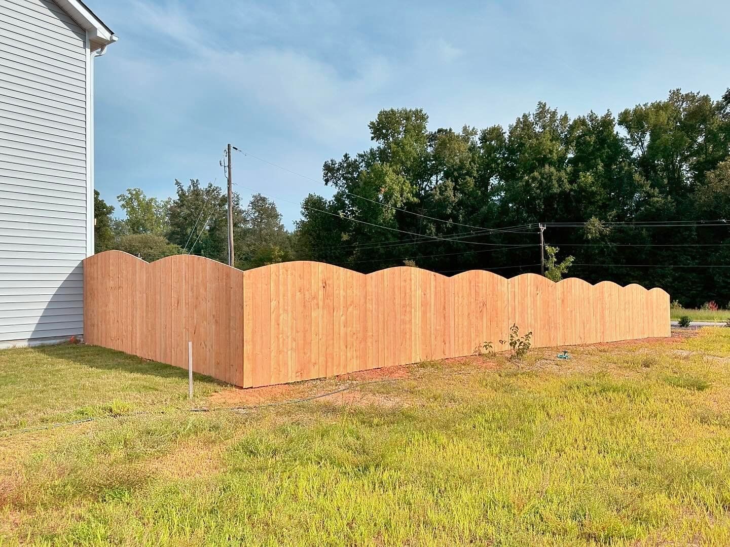 A wooden fence is sitting in the grass next to a house.