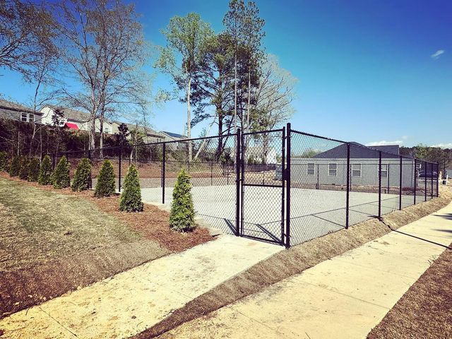 There is a tennis court behind a chain link fence.