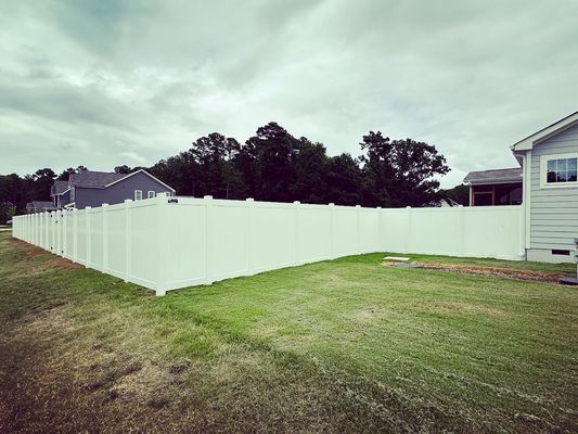 There is a white fence in the backyard of a house.