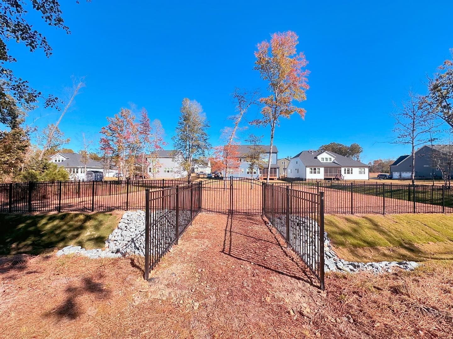 A dog park with a fence and a path leading to it.