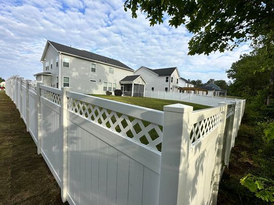 A white fence surrounds a large white house.