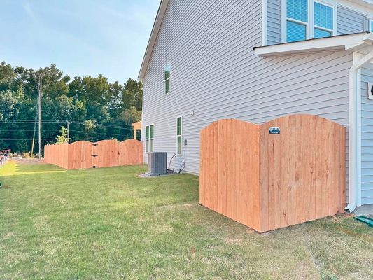A wooden fence is in the backyard of a house.