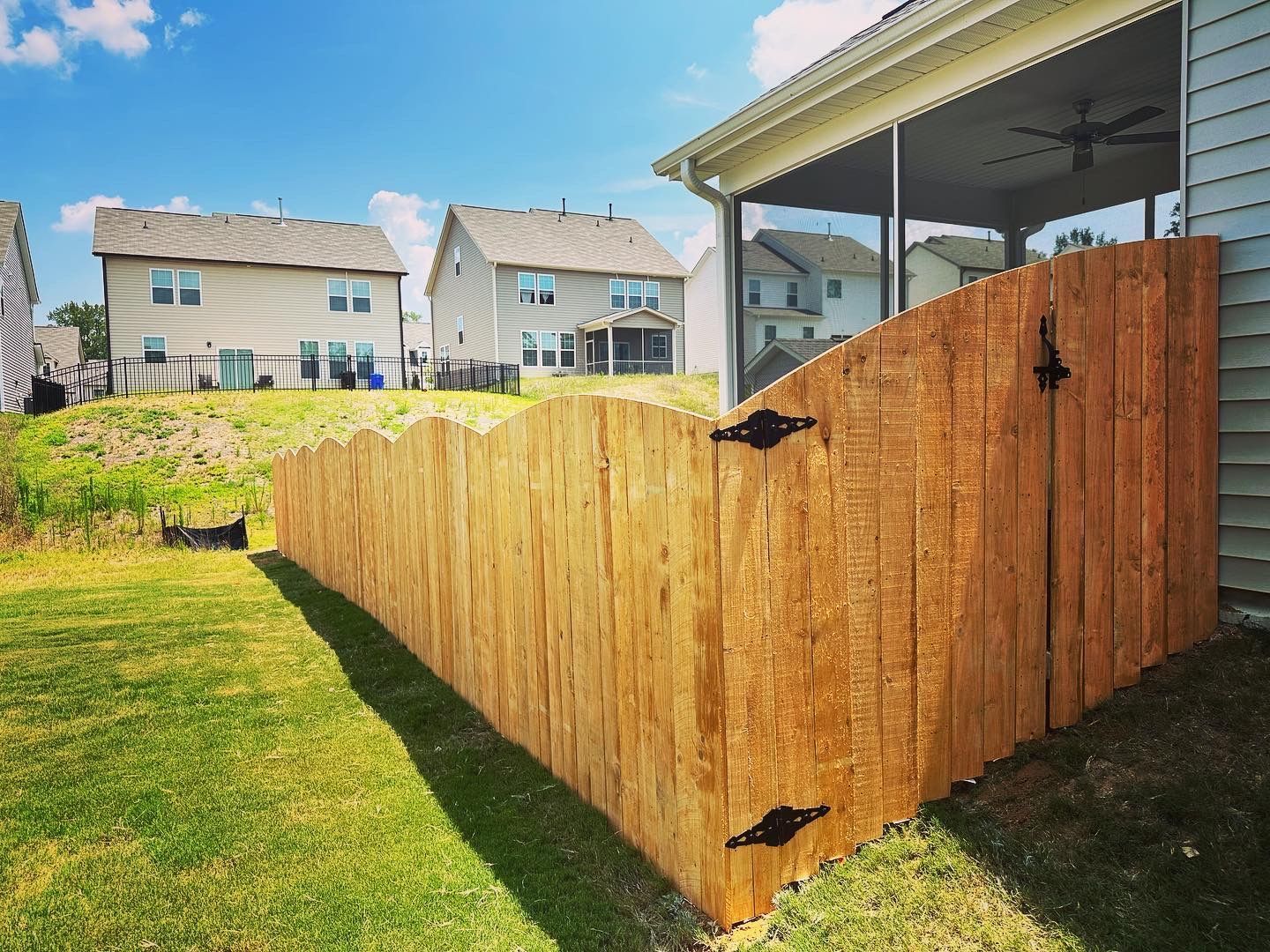 A wooden fence is in the backyard of a house.