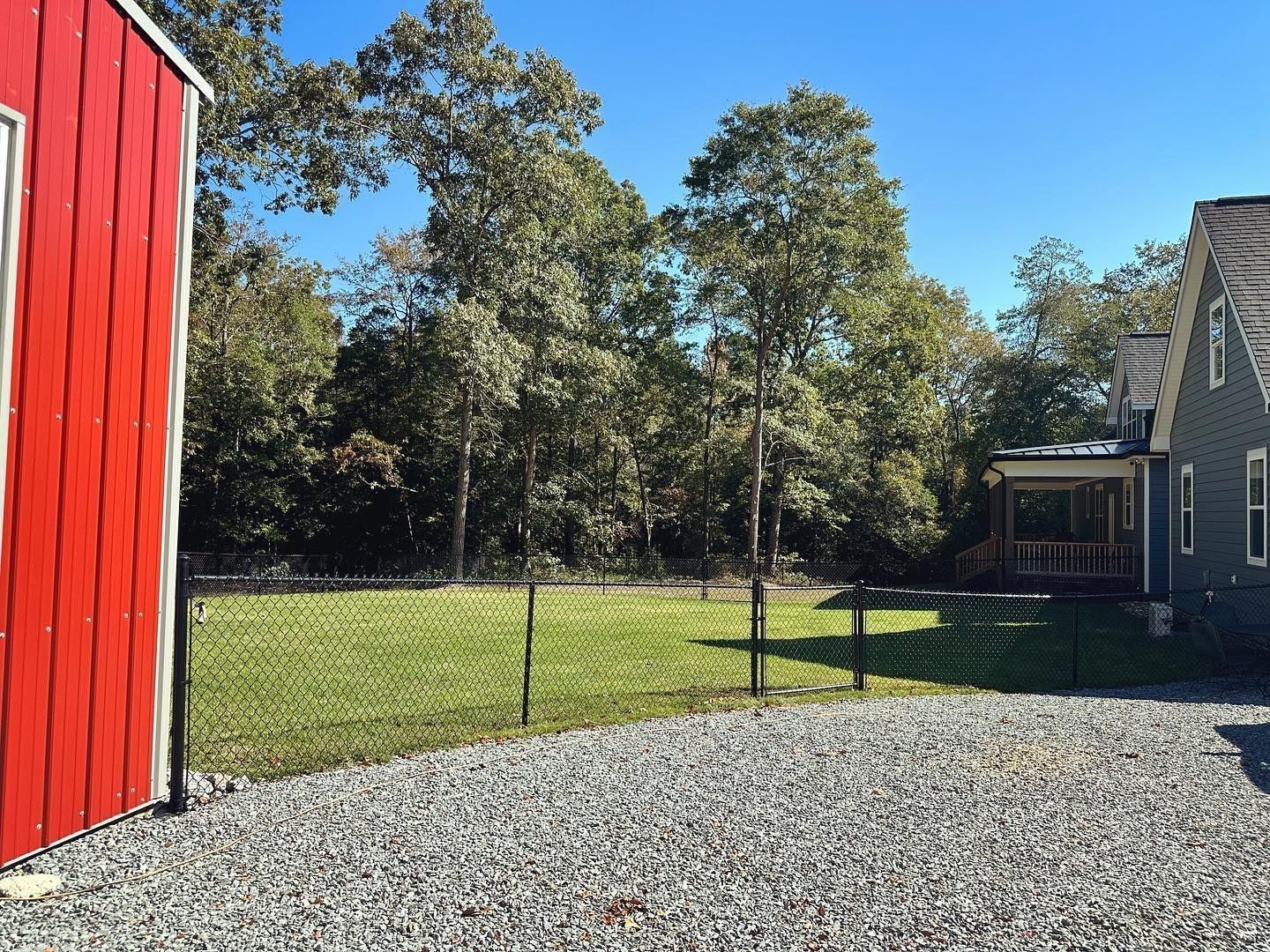 A red barn is next to a gravel driveway