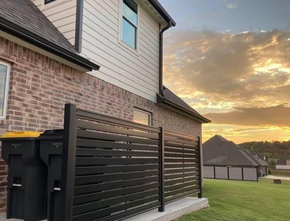A brick house with a black fence in front of it.