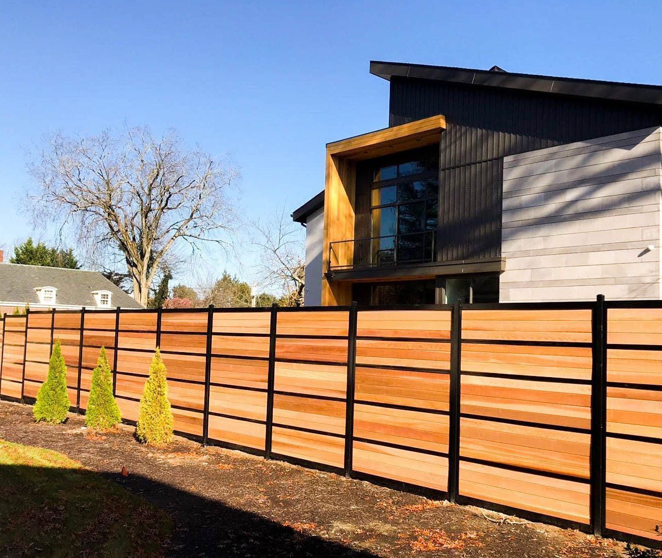 A wooden fence is in front of a house.