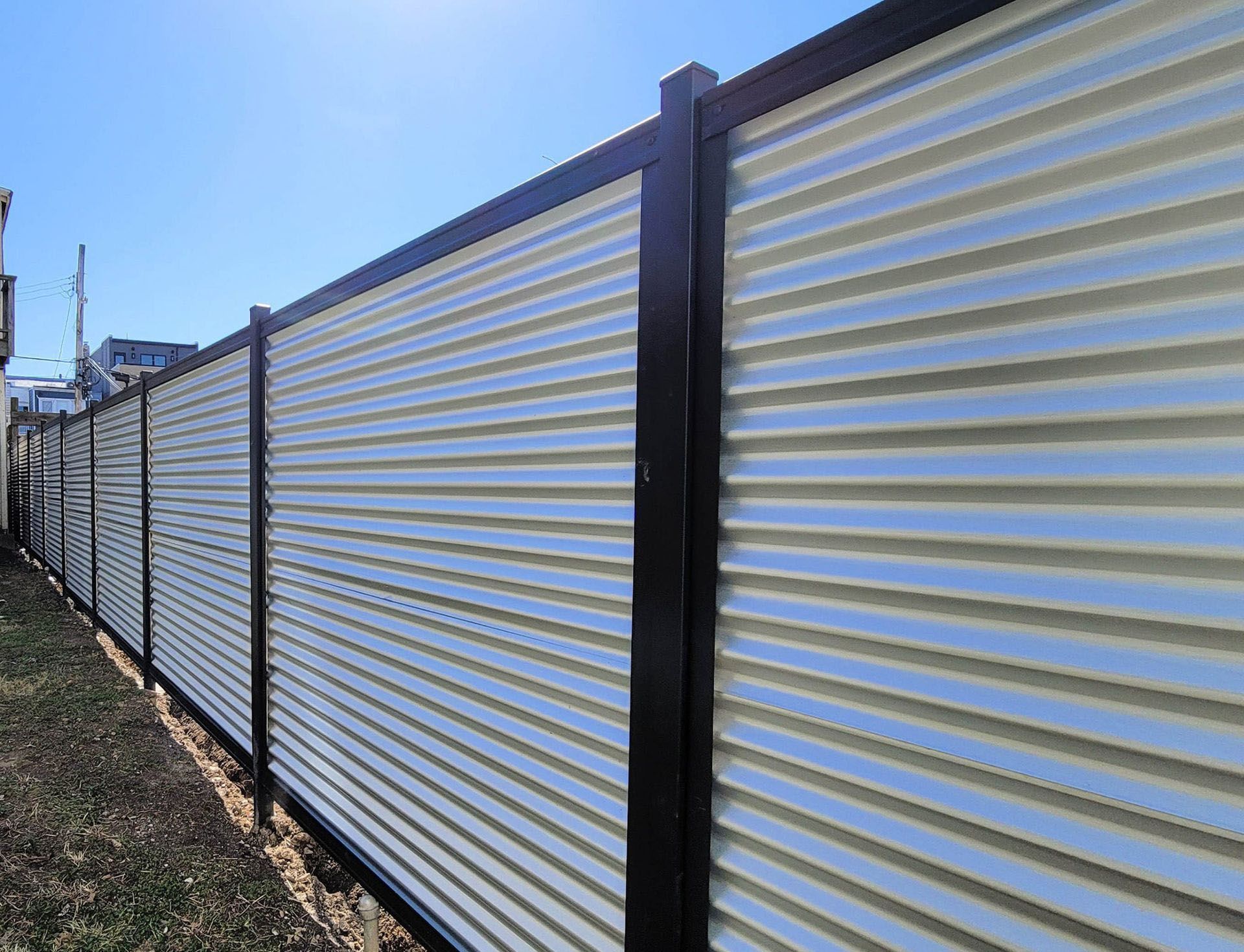 A white and black metal fence with a blue sky in the background.