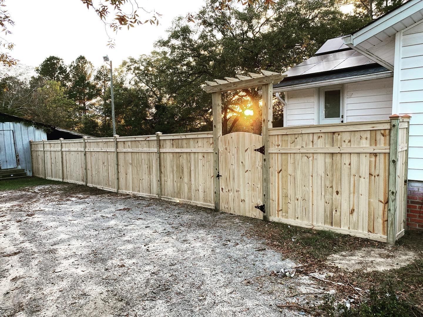 A wooden fence with a gate in front of a house.