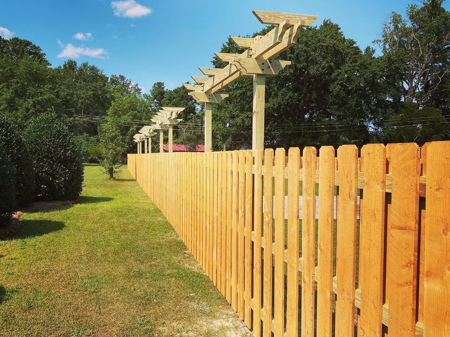 A wooden fence with a pergola on top of it.
