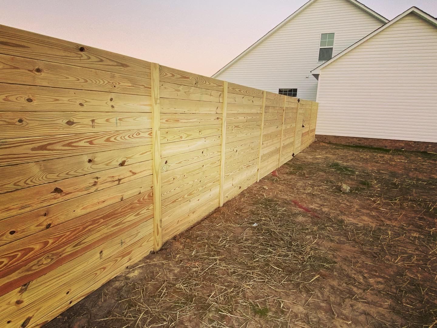 A wooden fence is in the backyard of a house.