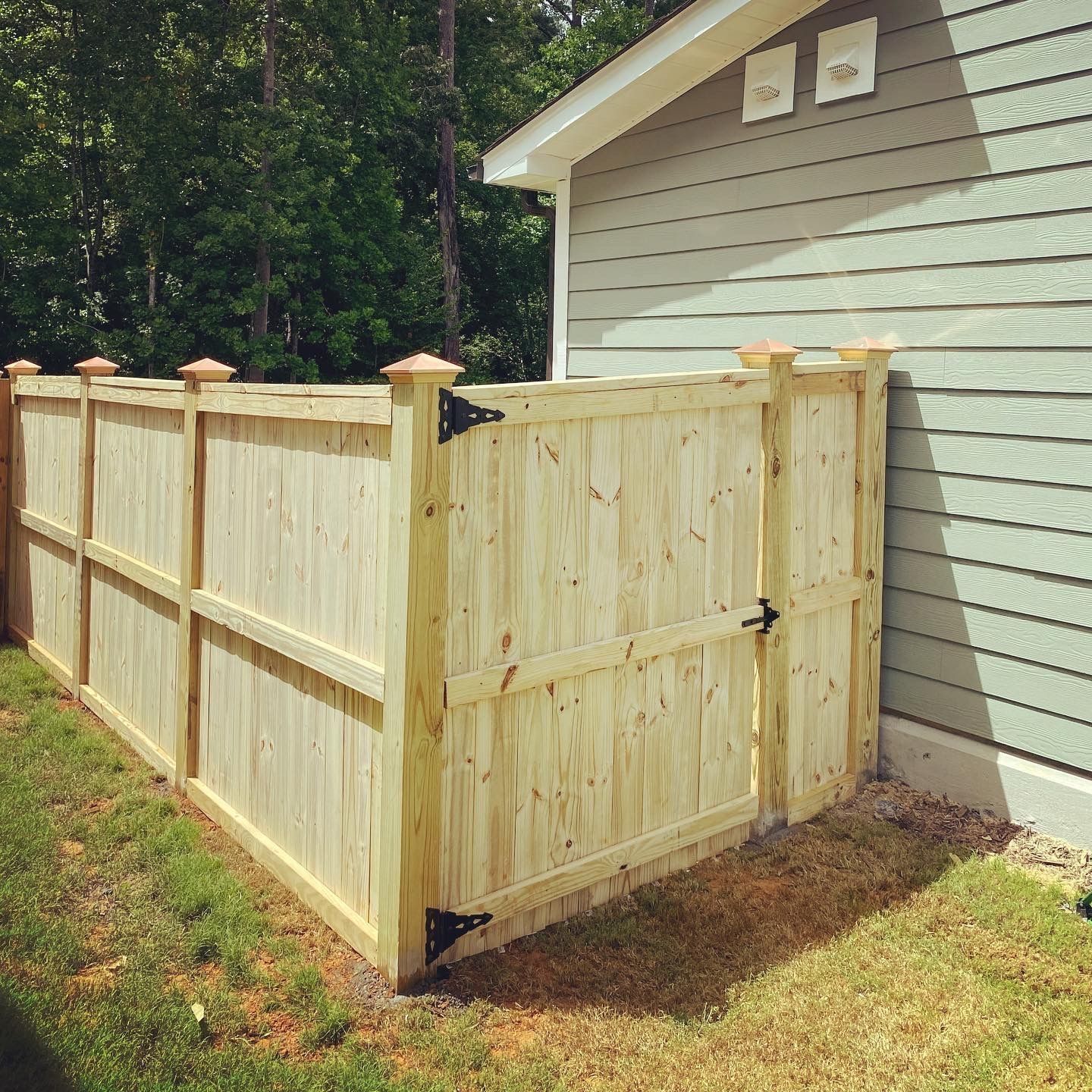 A wooden fence with a gate in front of a house