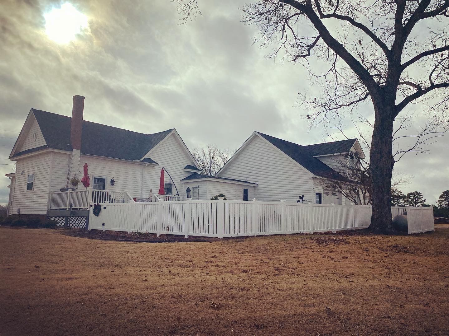 A white house with a white fence and a tree in front of it.