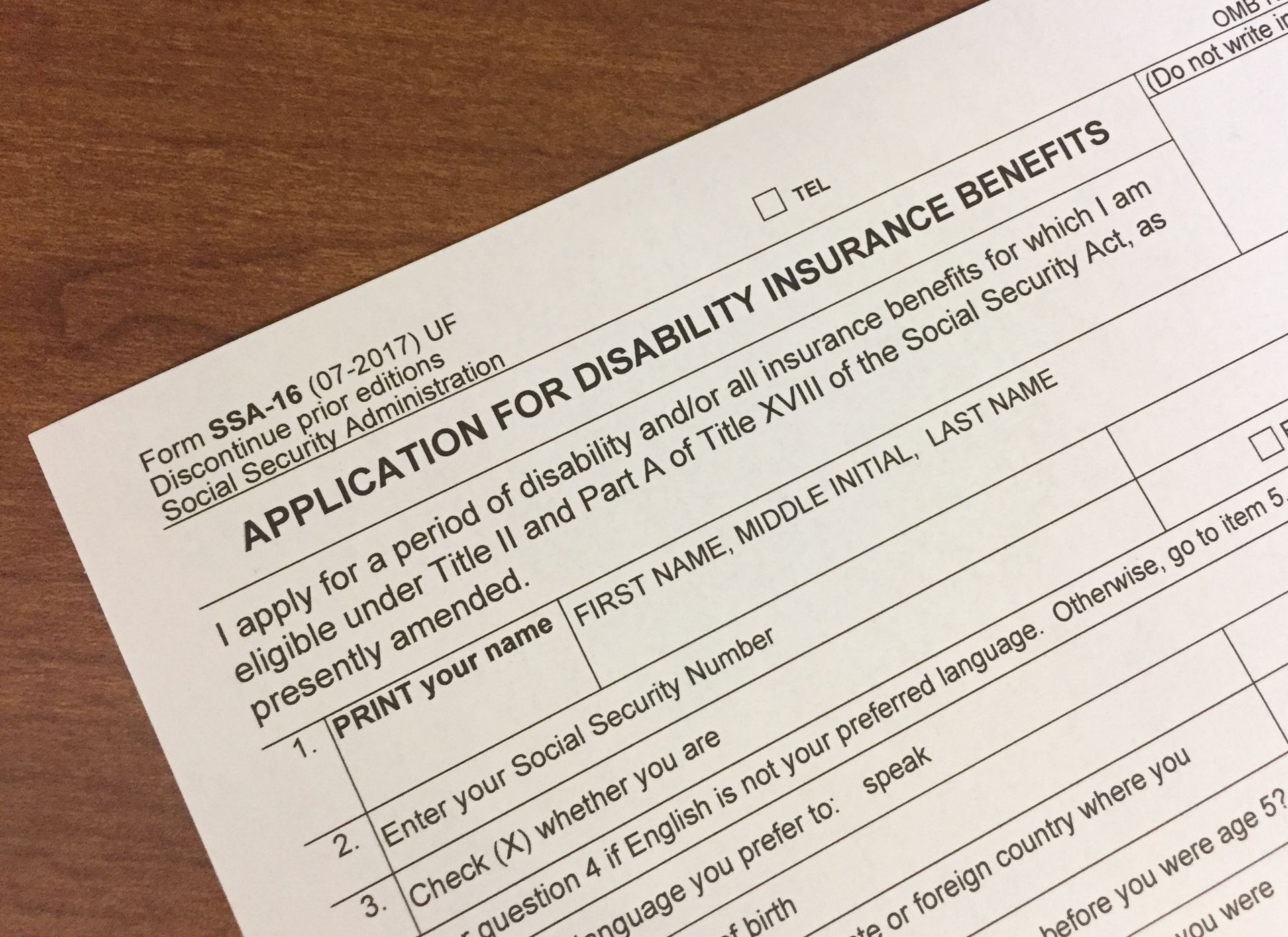 Application form for disability insurance benefits on wooden surface.