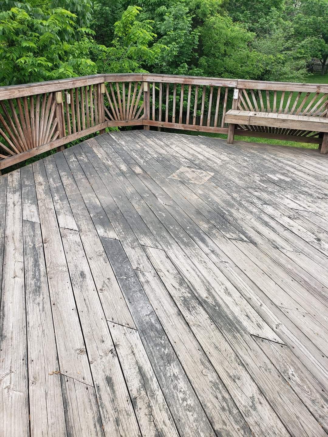 an empty wooden deck with a railing and a bench