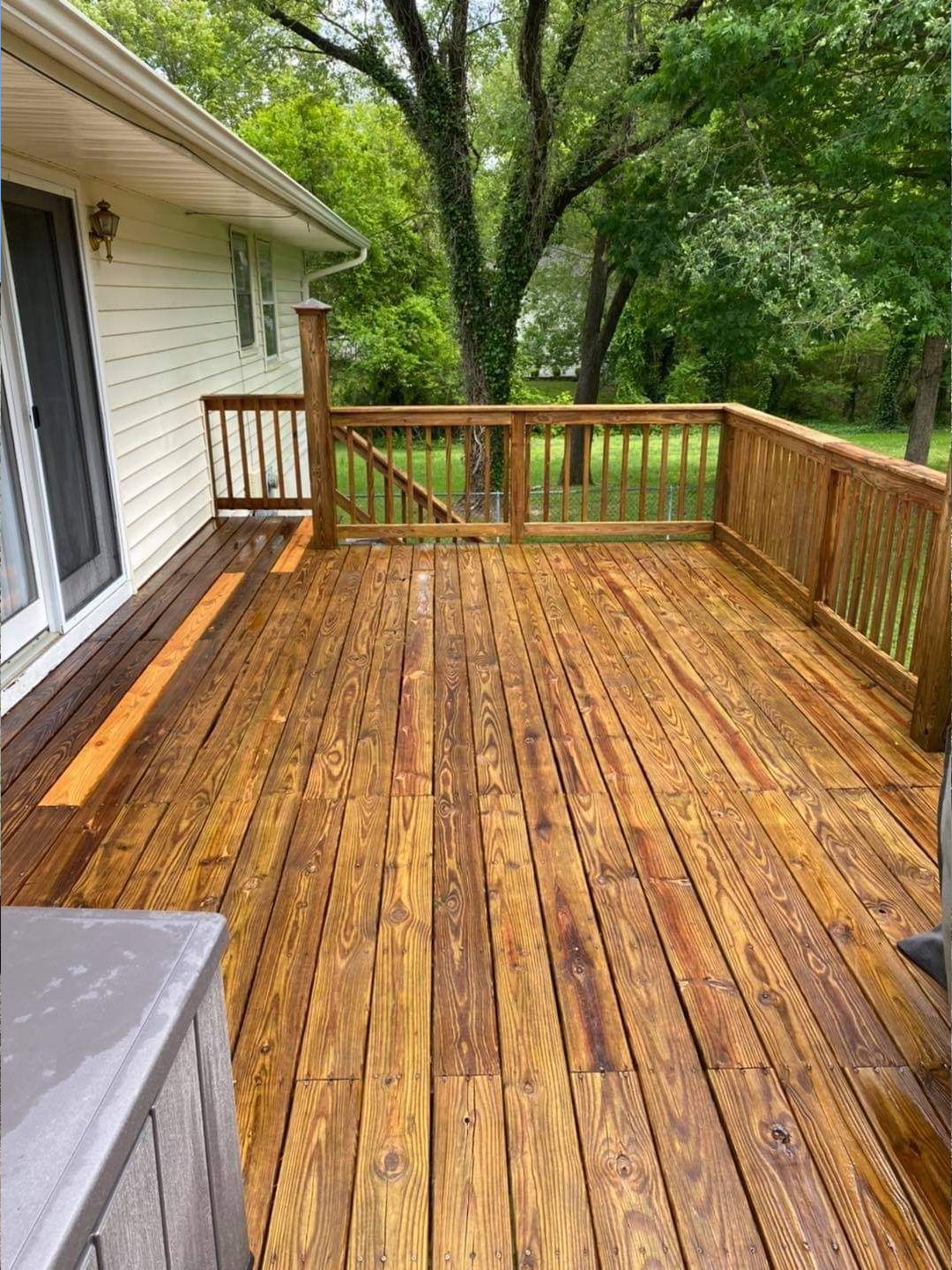 a large wooden deck in front of a house with trees in the background