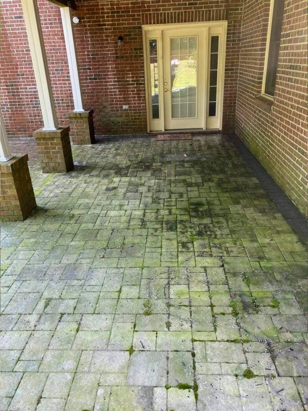 a patio with a brick wall and a door covered in moss