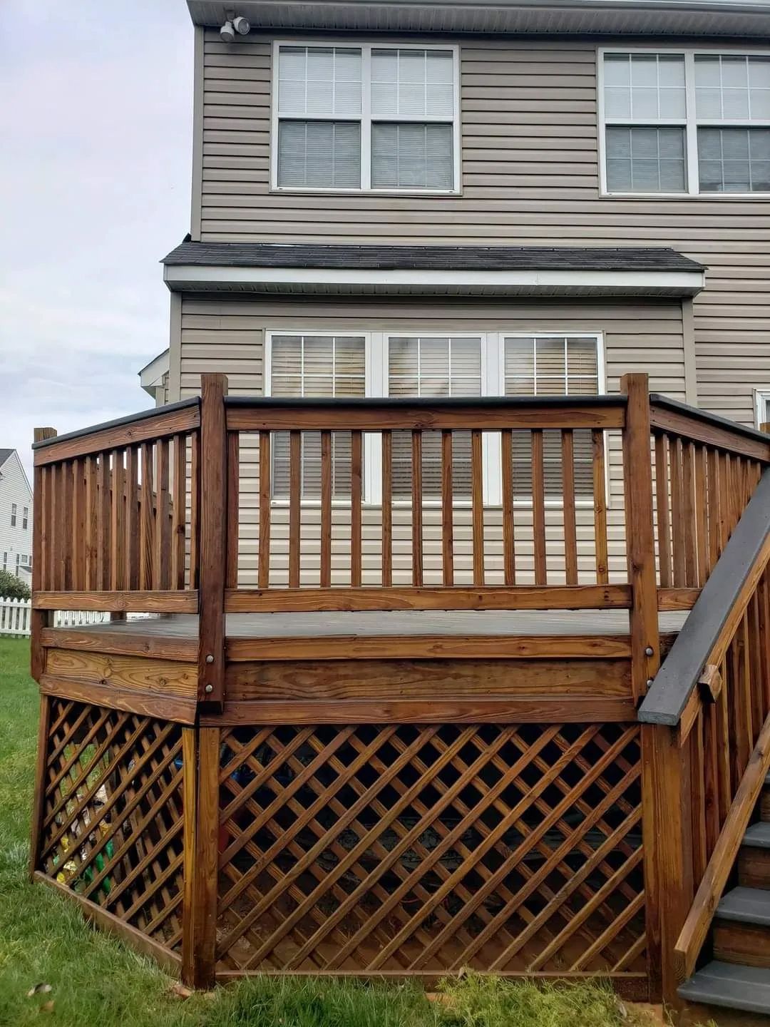 a wooden deck with stairs leading up to it is in front of a house