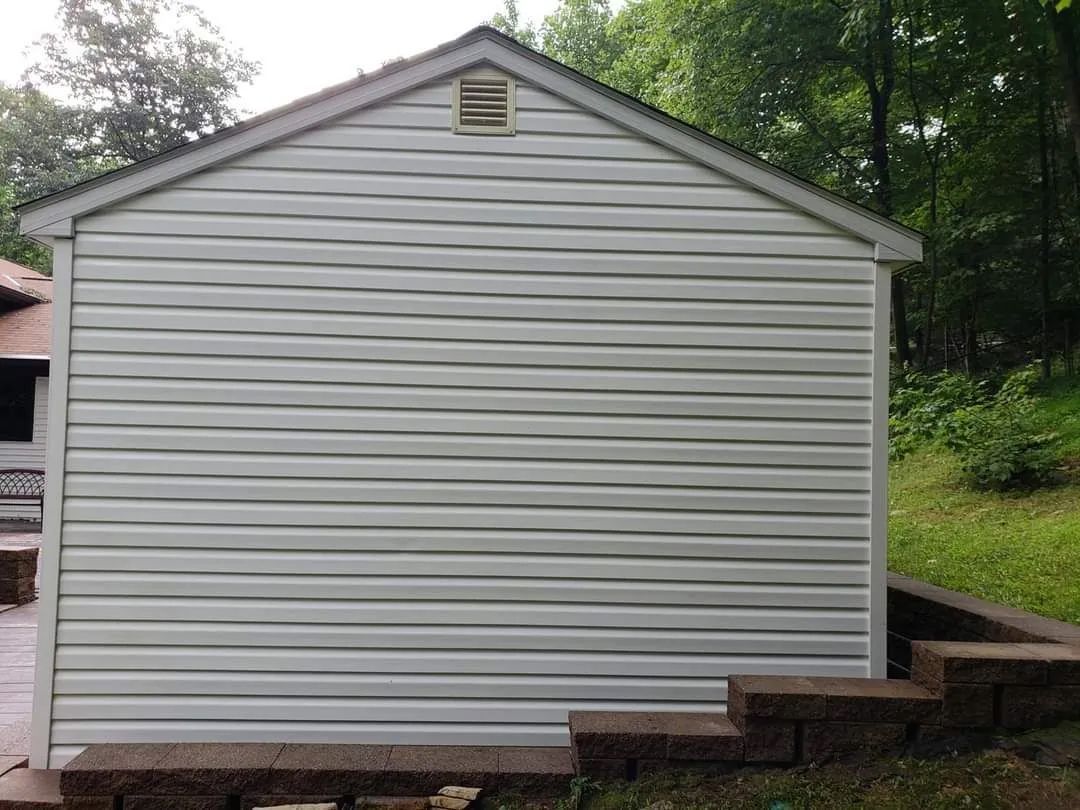 a white shed is sitting next to a stone wall in a backyard