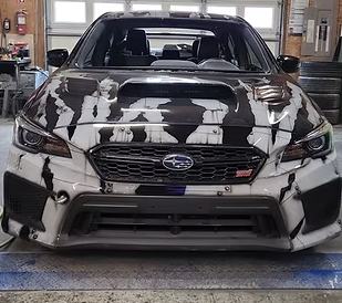 A black and white subaru wrx is parked in a garage.
