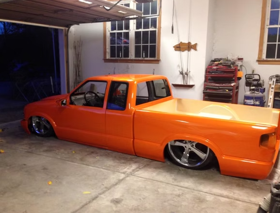 An orange pickup truck is parked in a garage