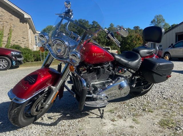 A red harley davidson motorcycle is parked in a gravel lot.