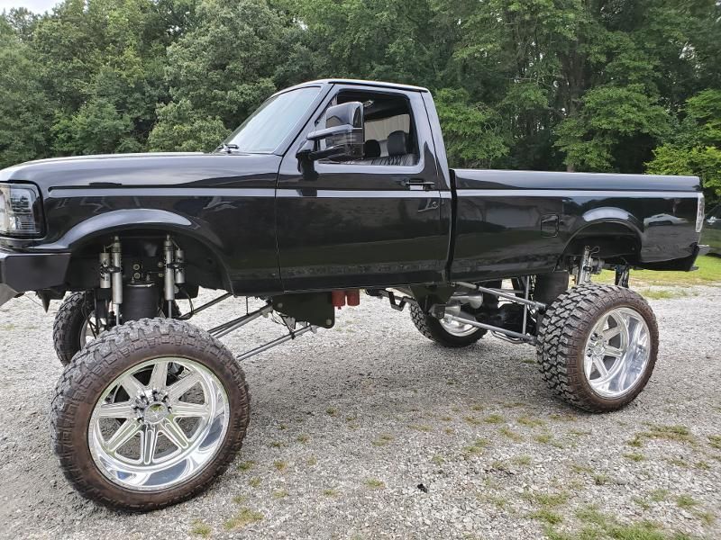 A black pickup truck is parked on a gravel road.