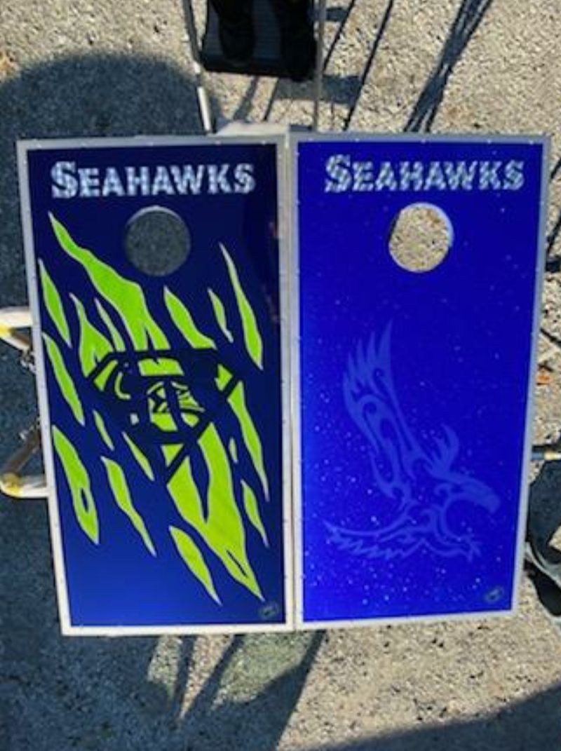 Two seahawks cornhole boards are sitting on the ground