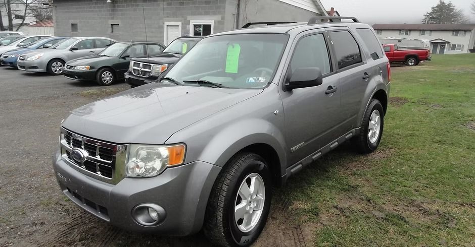 Gray SUV parked on a grassy lot in front of a building, with other cars nearby.