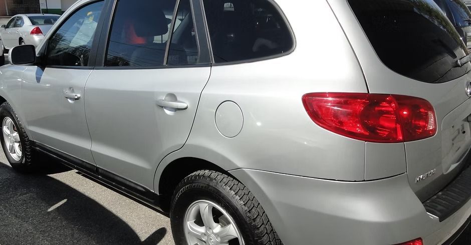 Silver SUV parked in a lot, rear side view with red taillights visible