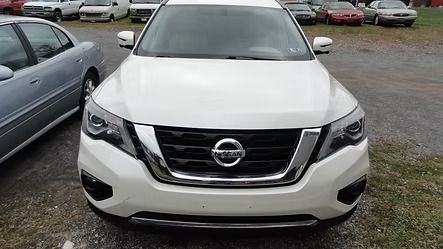 Front view of a white Nissan SUV parked in a lot with other cars behind it