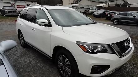 White SUV parked in a lot on a rainy day, front-left view