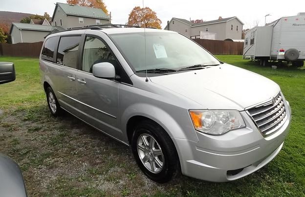 Silver minivan parked on grass in a suburban neighborhood