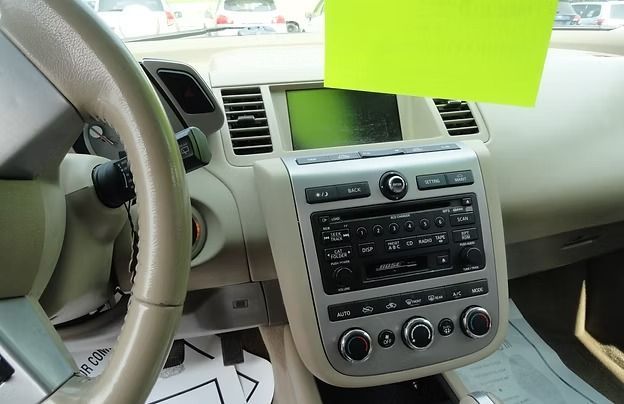 Car dashboard with steering wheel and center console, featuring a built-in radio and climate controls.