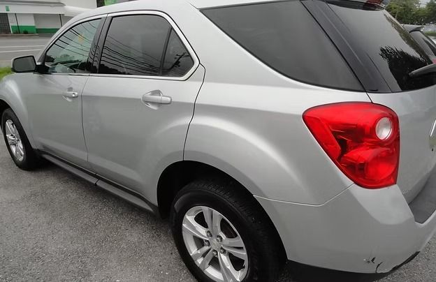 Silver SUV parked on a paved surface, rear side view with red taillights