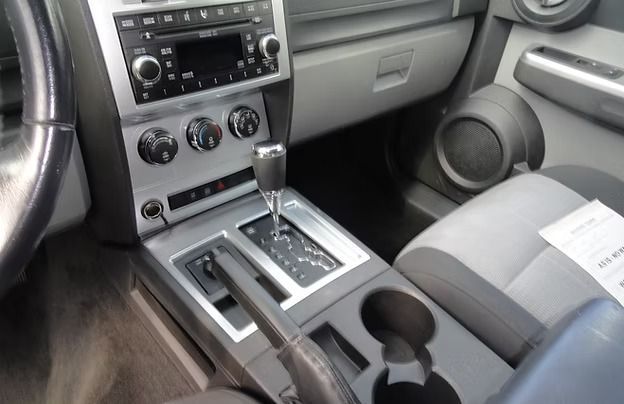 Car interior with silver center console, gear shift, cup holders, and gray passenger seat