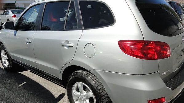 Silver SUV parked in a lot, rear side view with red taillights visible