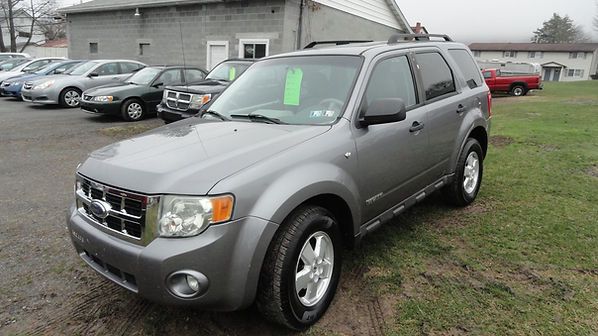Gray SUV parked on a grassy lot beside a building, with other cars in the background.