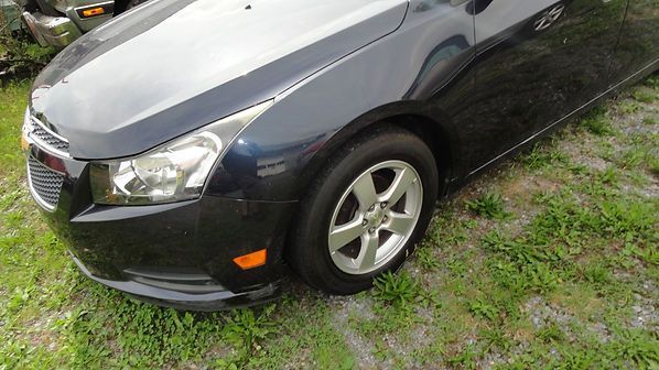 Dark blue sedan parked on grass, front-left view, with silver wheel and headlight visible