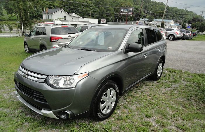 Gray SUV parked on a grassy lot with other cars in the background