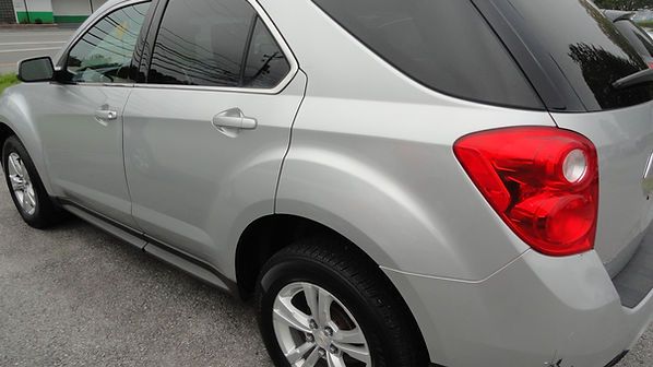 Silver SUV parked on a wet street, rear side view with red taillight visible