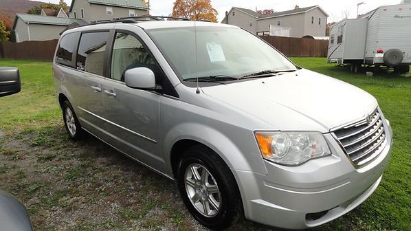 Silver minivan parked on grass in a suburban neighborhood driveway
