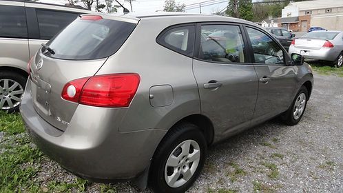 Gray compact SUV parked on gravel lot, rear three-quarter view with red taillights visible