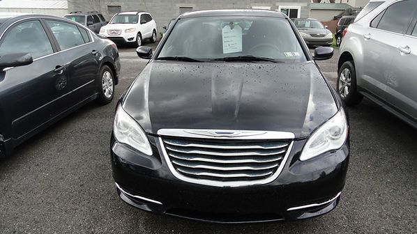 Front view of a black sedan parked between two cars in a lot