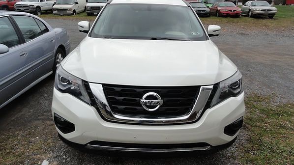 Front view of a white Nissan SUV parked in a lot on a rainy day
