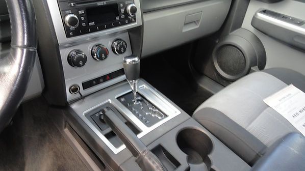Car interior with center console, automatic gear shift, radio controls, cup holder, and gray passenger seat
