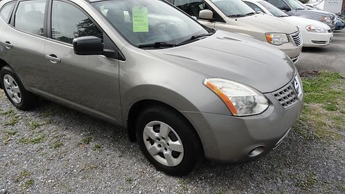 Silver compact SUV parked on a gravel lot with other cars in the background