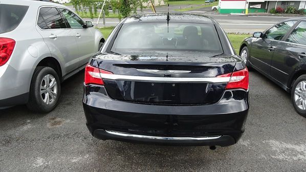 Black sedan parked between two cars in a wet parking lot.