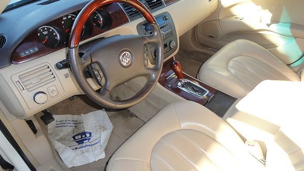 Cream leather car interior with steering wheel, dashboard, center console, and a plastic bag on the floor.
