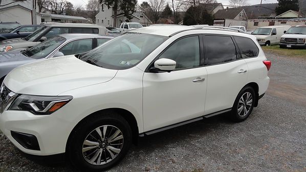 White SUV parked in a lot with other cars and houses in the background